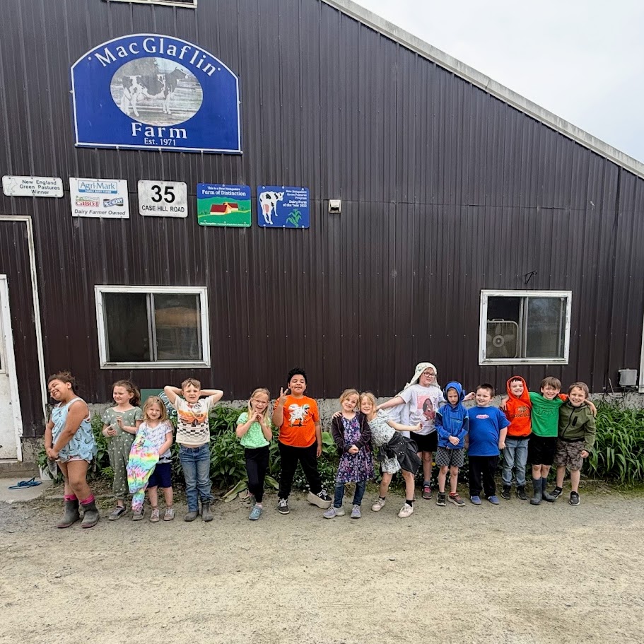 A group of students stand in front of the MacGlafin barn